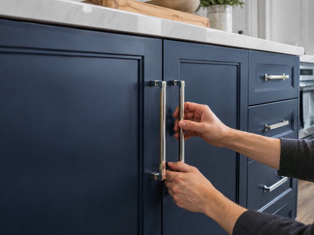 Hands fit long bar handles on navy painted cabinet doors